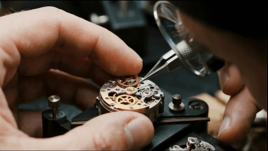 Watchmaker assembling a precision movement under a loupe